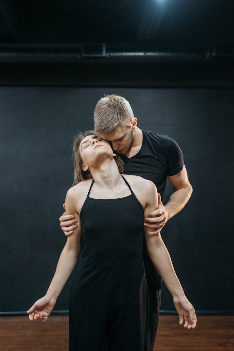 A Man In Black Shirt Holding Her Partners Arms