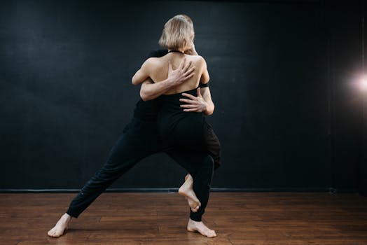 Two dancers passionately performing in a studio setting with a black background.