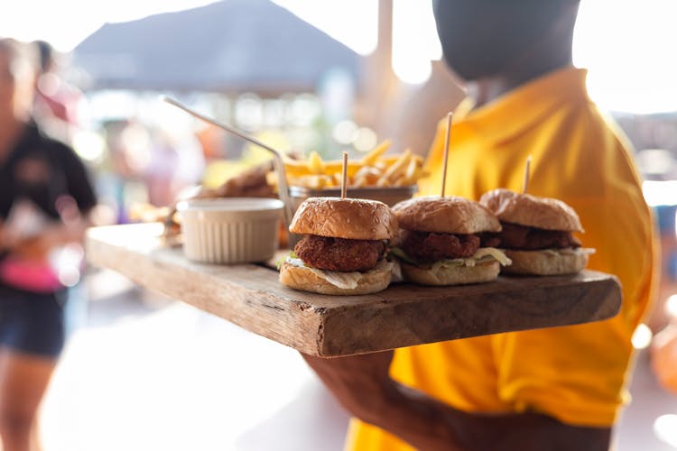 Close-Up Shot Of A Person Holding A Wooden Tray With Burgers