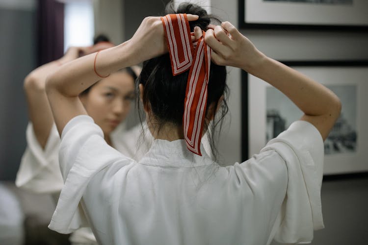 Close-Up Shot Of A Woman In White Robe Tying Her Hair In Front Of A Mirror