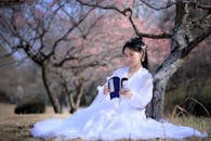 Woman in White Dress Sitting Under the Tree Reading a Book