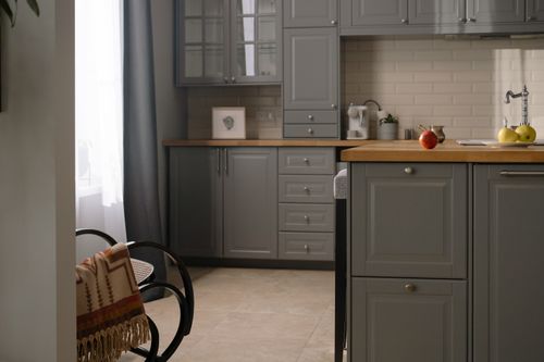 Free Stylish gray kitchen interior with wooden countertops, natural lighting, and modern design elements. Stock Photo
