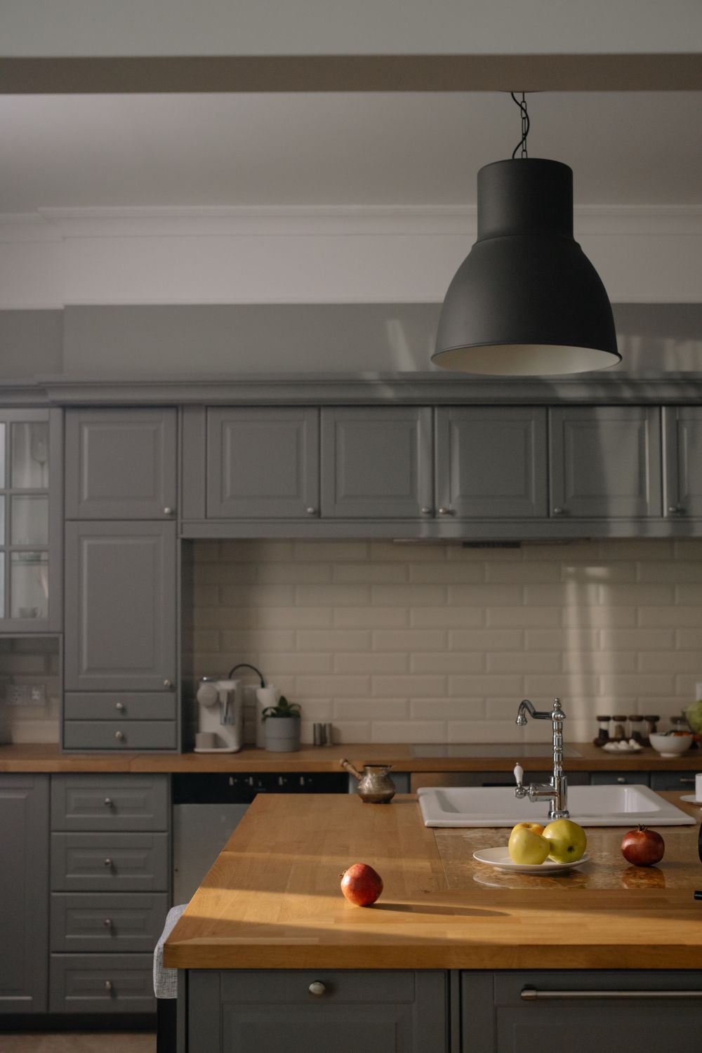 Kitchen cabinetry, wooden countertop, sink, backsplash and pendant lighting