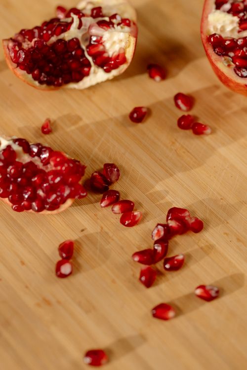 Free Pomegranate slices and seeds scattered on a wooden background, showcasing vibrant red hues of healthy fruit. Stock Photo