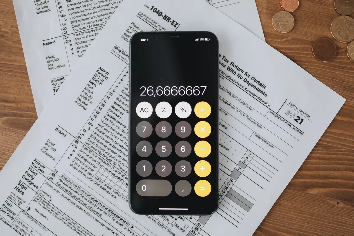 Tax forms and a calculator on a desk, representing the paperwork of filing capital gains and losses.