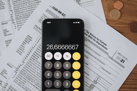 Smartphone calculator over tax forms with coins, symbolizing tax calculation and finance.