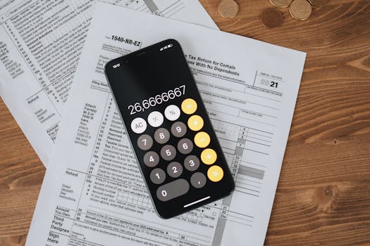 Overhead view of smartphone calculator on tax forms for finance and accounting.