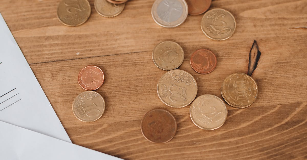 Photo by Polina Tankilevitch Coins scattered on a wooden surface alongside tax documents, evoking financial themes.