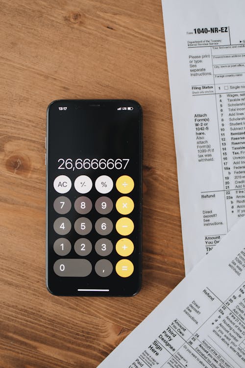 Free Tax Forms Beside A Calculator On Wooden Surface Stock Photo