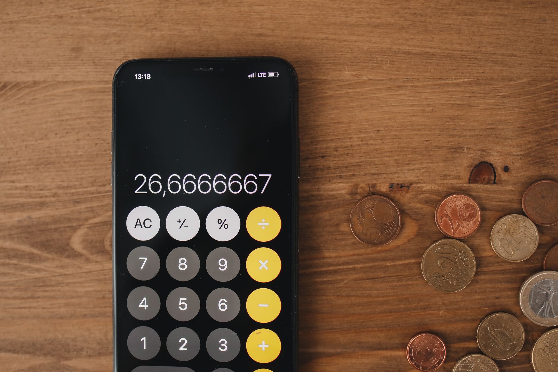 Close-up view of smartphone calculator and coins on wooden surface for financial metaphor.