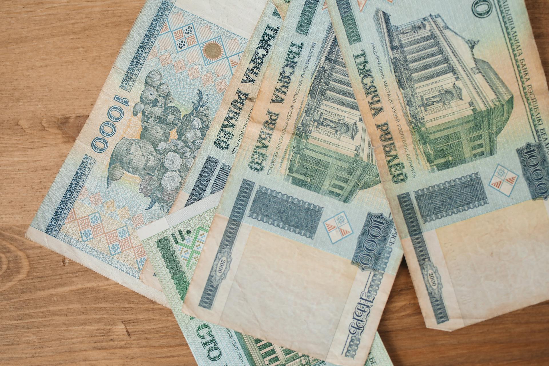 Close-up of Belarusian ruble banknotes spread out on a wooden surface.