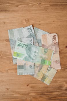 Close-up of Indonesian Rupiah banknotes scattered on a wooden table, showcasing various denominations.