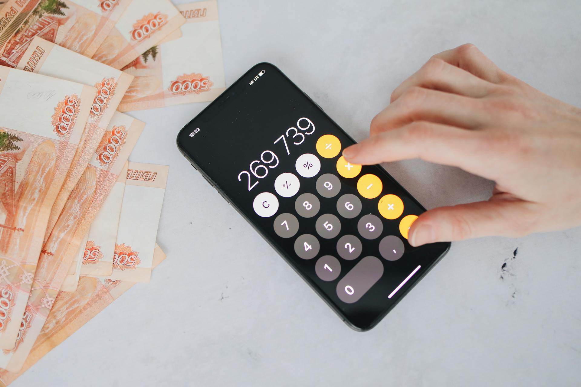 Person using smartphone calculator with Russian rubles on a table, representing financial planning.