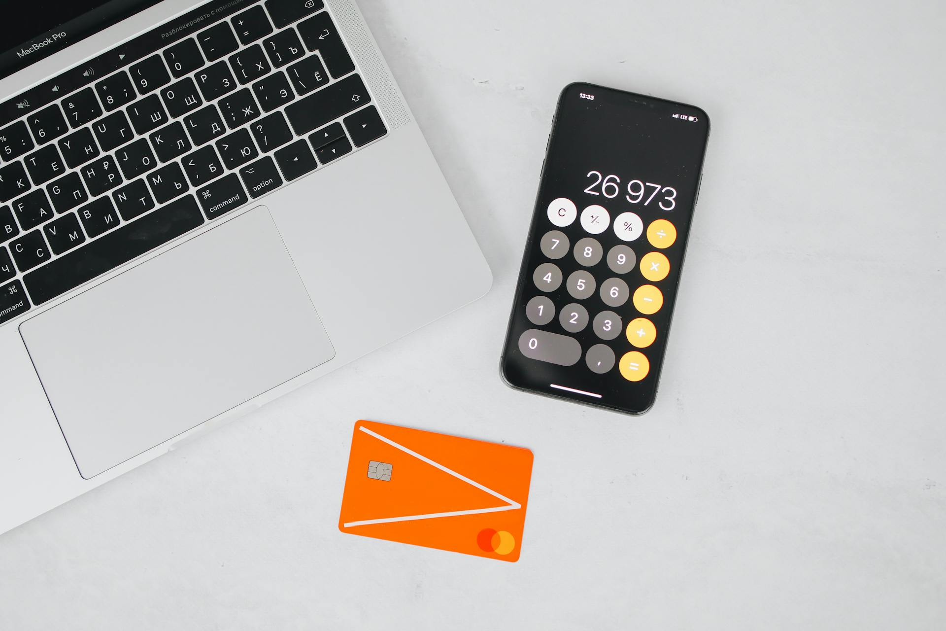 A Macbook Pro with Mobile Phone and Credit Card on a White Surface