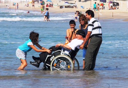 A family spends quality time at Tel Aviv beach, smiling and enjoying togetherness.