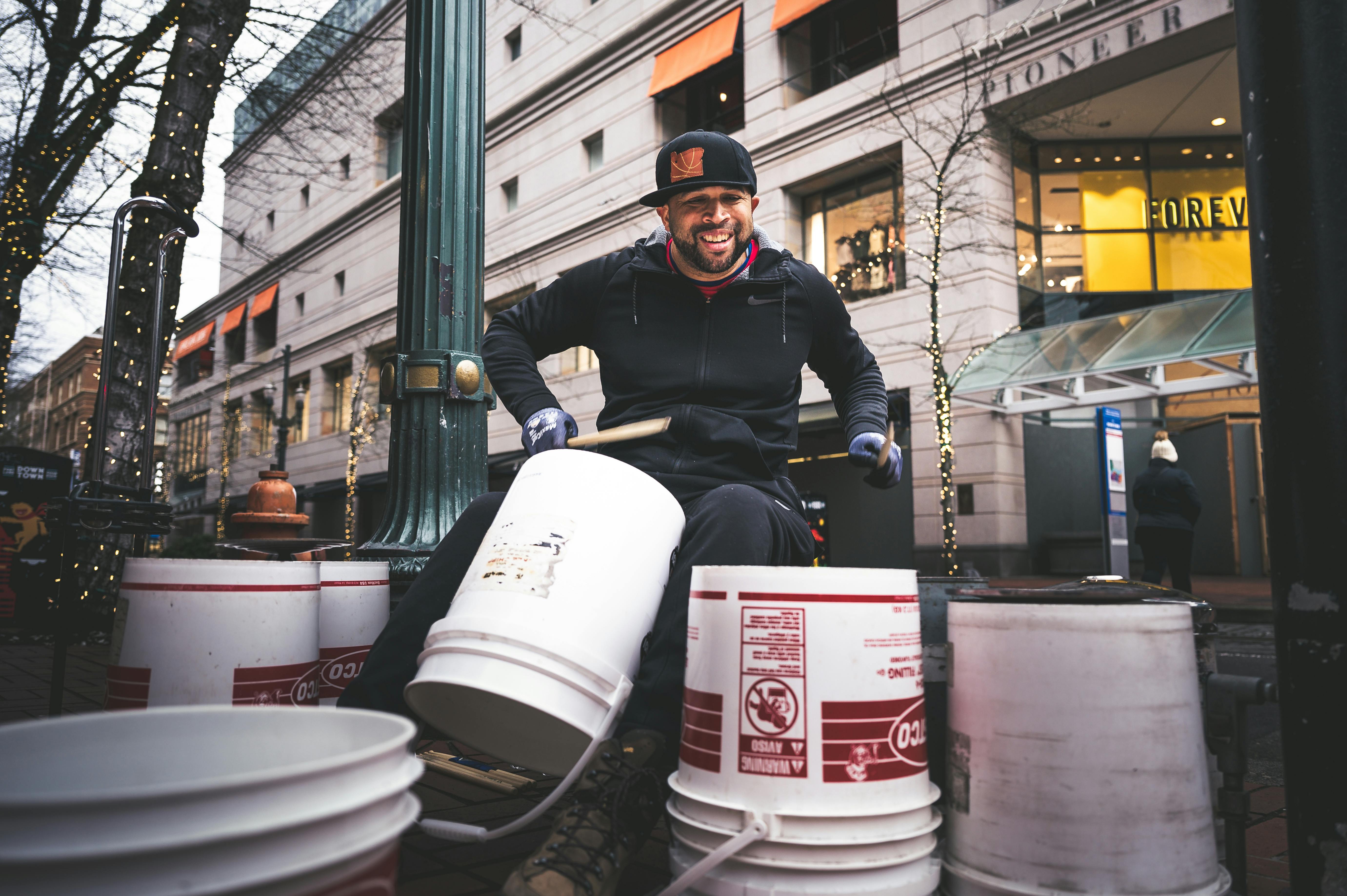 Happy man drumming on buckets · Free Stock Photo