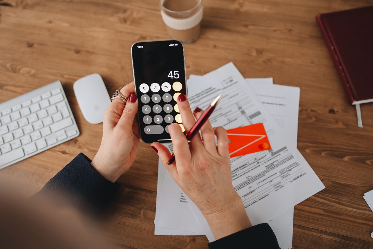Person checking phone and utility bill statements at home