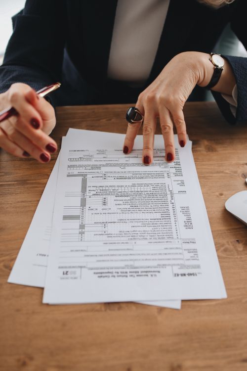 Free Hands with manicured nails examining tax forms on wooden table indoors. Stock Photo