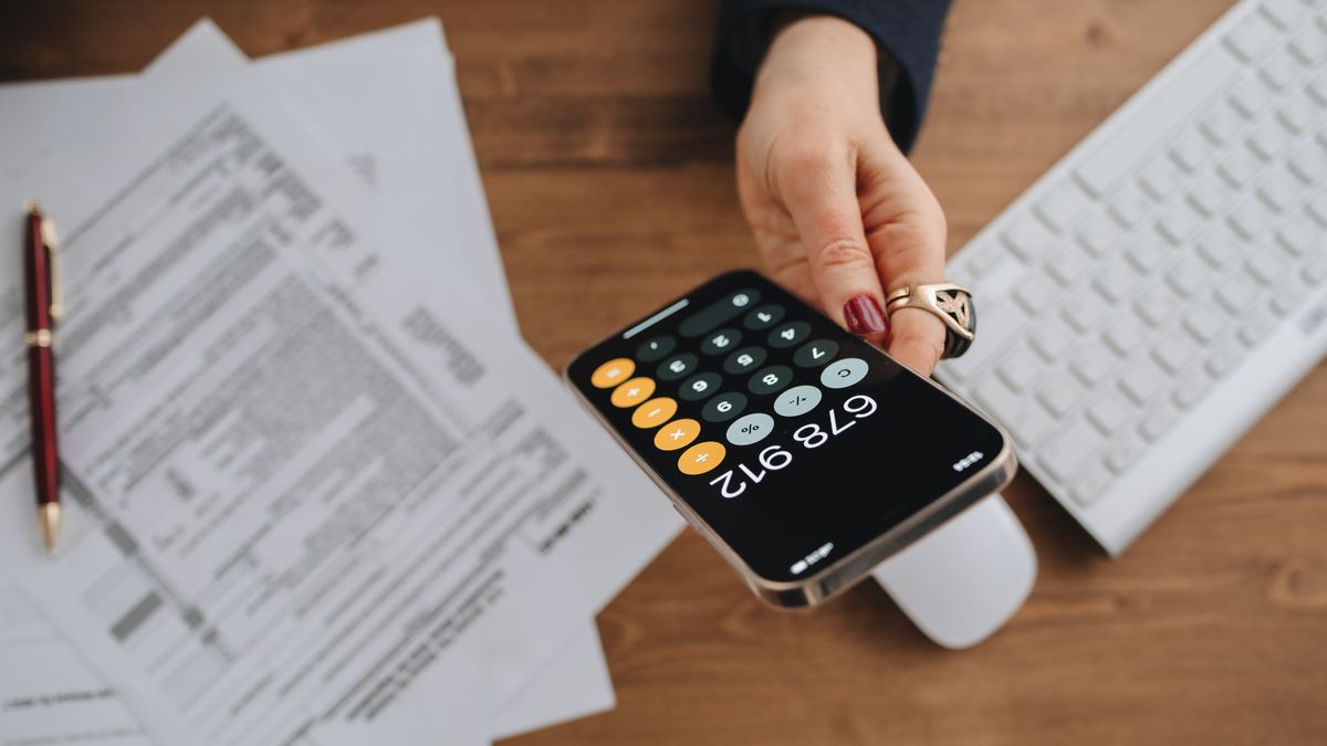 スマートフォンの電卓で書類を確認しながら計算している手元のイメージ