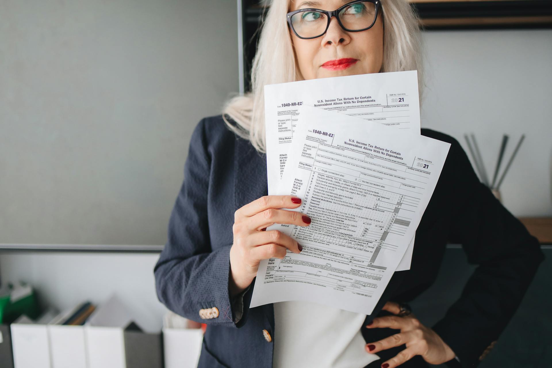 Businesswoman presenting tax documents in a modern office setting.