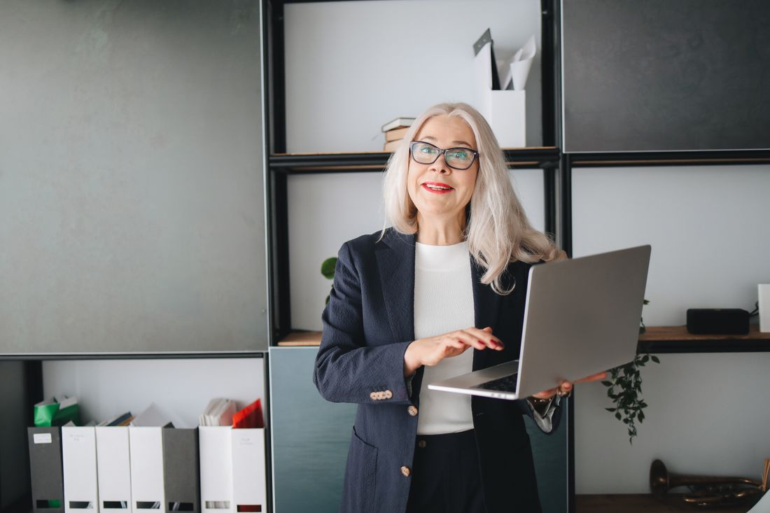 Senior businesswoman with eyeglasses using a laptop indoors