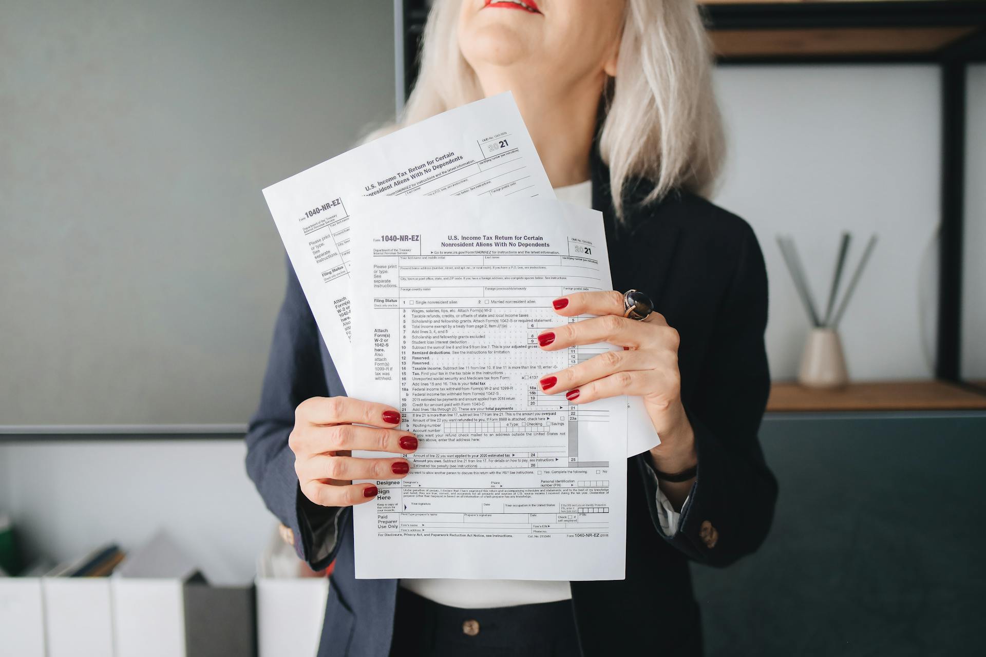 Businesswoman holding tax documents, ready for filing or review, in a professional office setting.