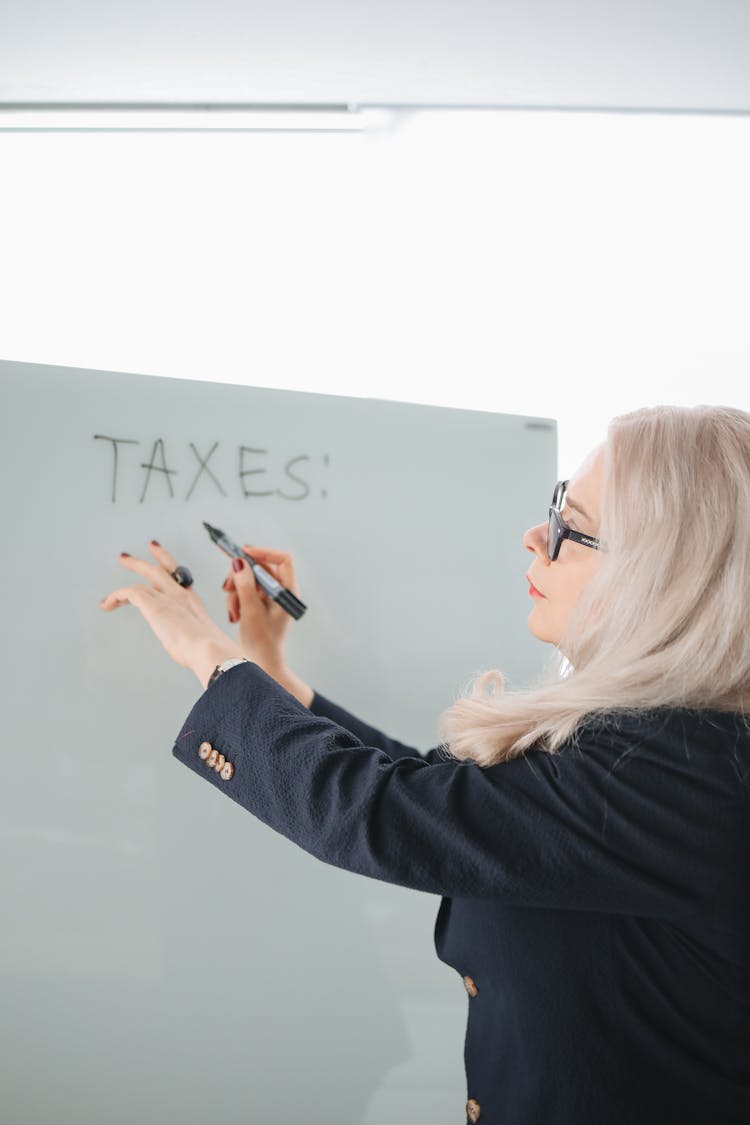 A Woman In Black Blazer Writing On White Board