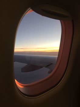 Stunning view of the sunset sky through an airplane window, showcasing the beauty of travel.