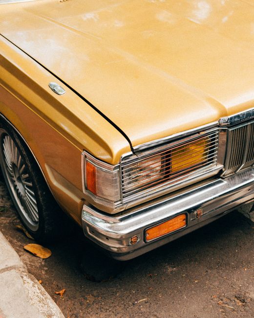 A vintage gold classic car parked on a street, showcasing its front detail.
