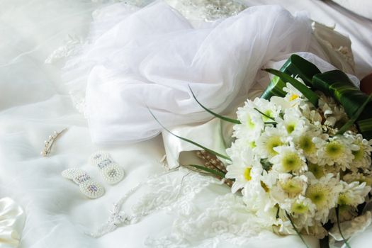 Elegant arrangement of bridal accessories with a white floral bouquet and veil, perfect for wedding themes.
