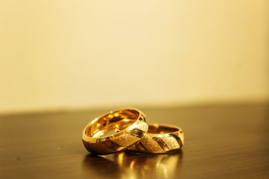 Close up of gold wedding rings symbolizing love and commitment on a wooden table.