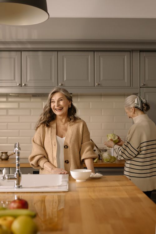 Free Senior women cooking together in a stylish kitchen, showcasing joyful expressions and food preparation. Stock Photo