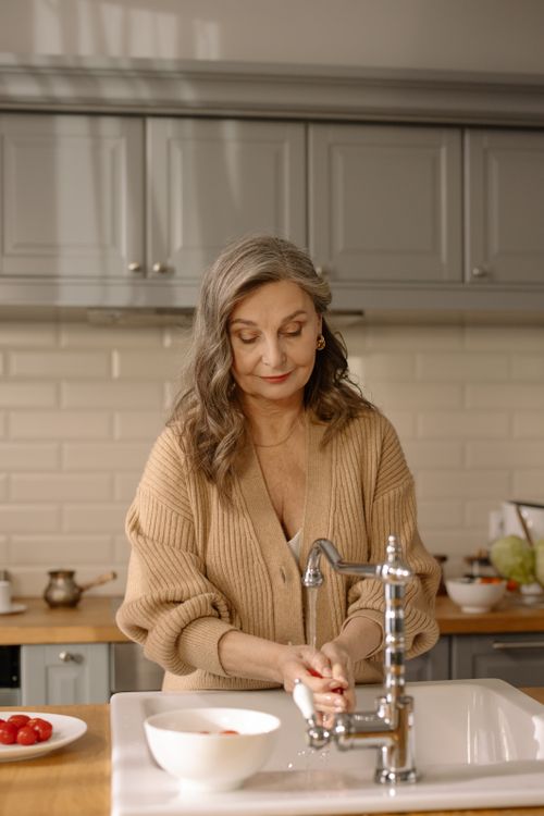 Free Elderly woman washing hands in a modern kitchen, showcasing healthy lifestyle and hygiene. Stock Photo
