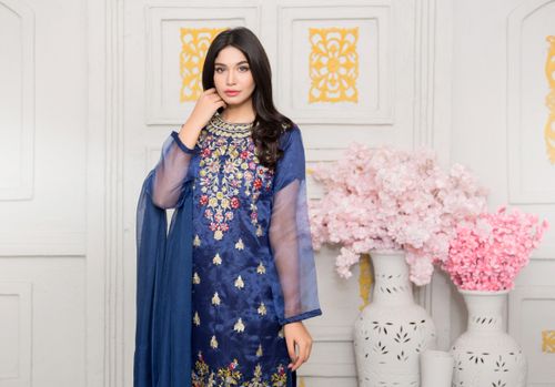 Free A stunning woman poses indoors in a beautiful blue embroidered sari, surrounded by pink flowers. Stock Photo