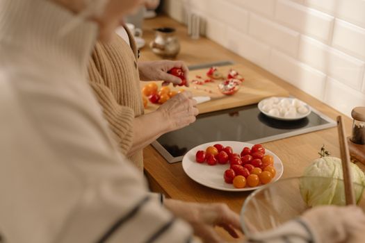 Two adults prepare a fresh salad with cherry tomatoes and cabbage in a warm, inviting kitchen.