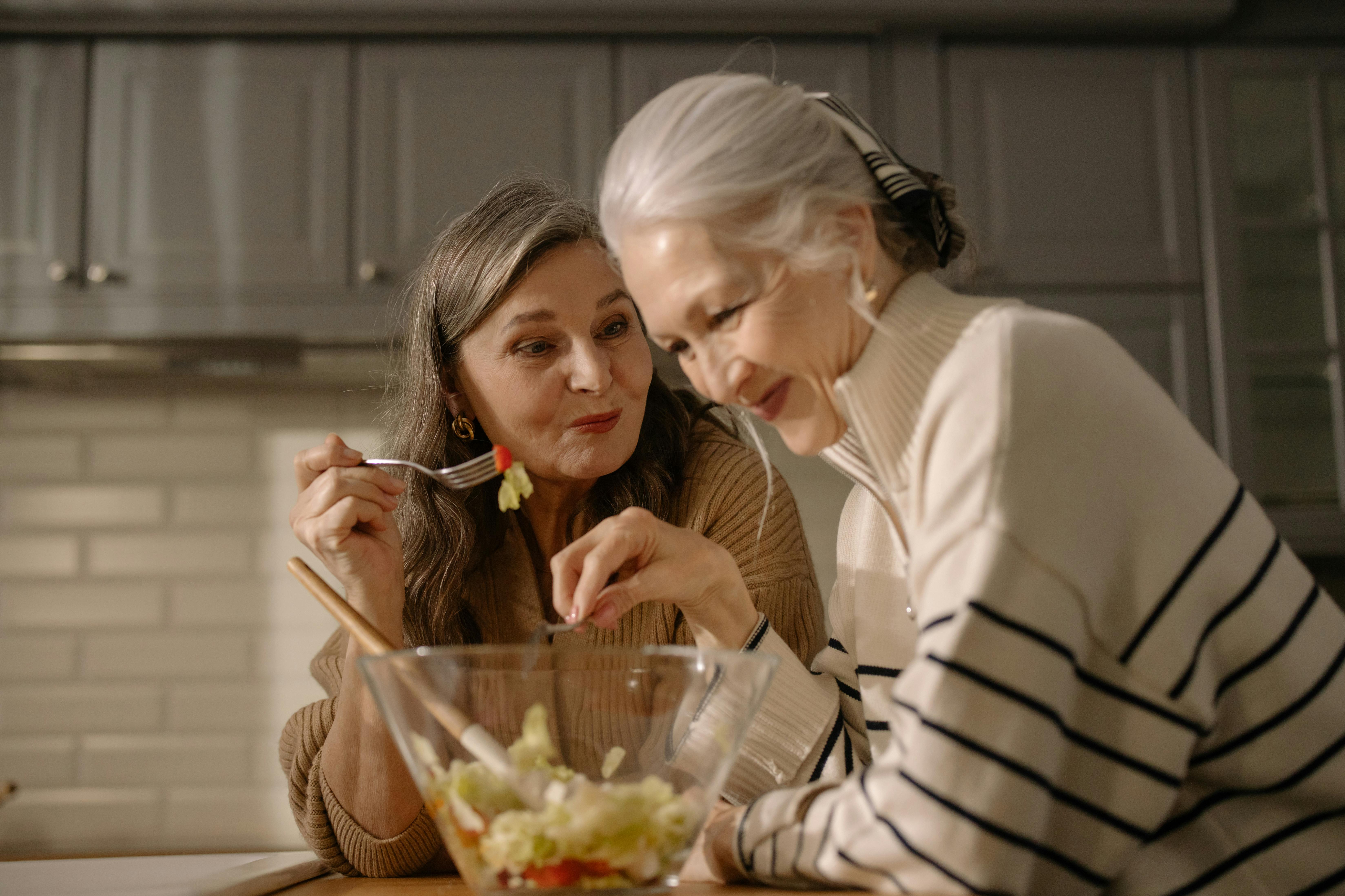 an elderly women eating salad in the kitchen