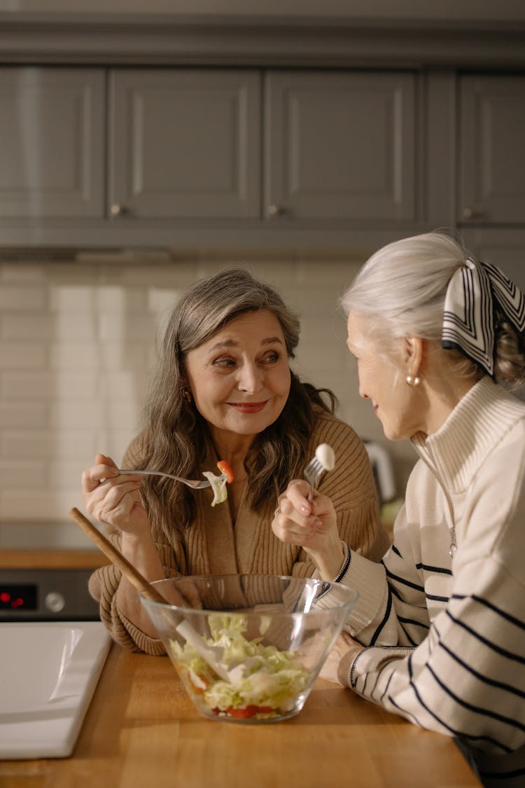 An Elderly Woman Looking At Each Other While Holding Fork