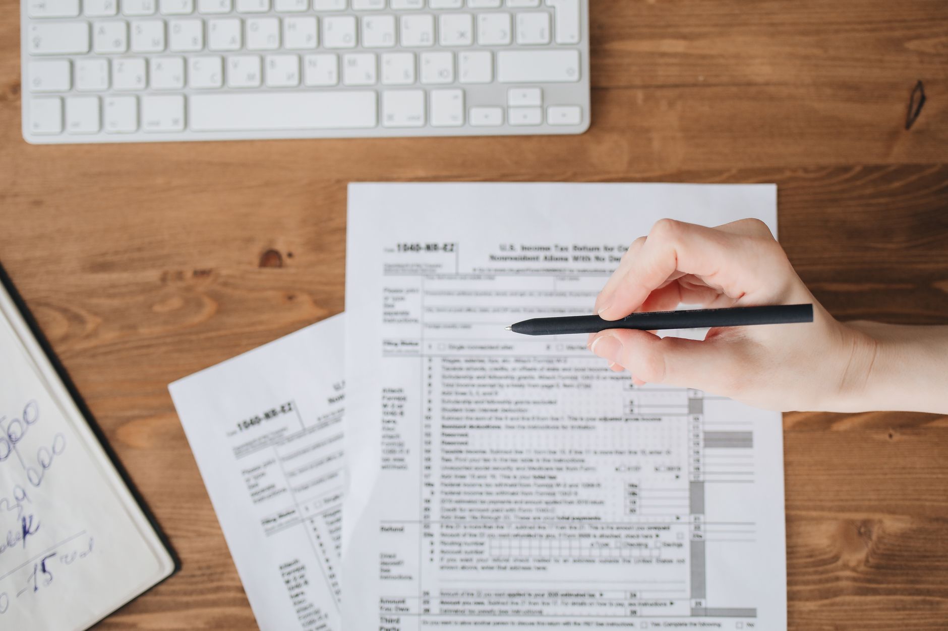 Close-up of a hand holding a pen over a printed form, checking the details on the first page of a disclosure