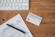 A Debit Card with Paper and Pen on a Wooden Table