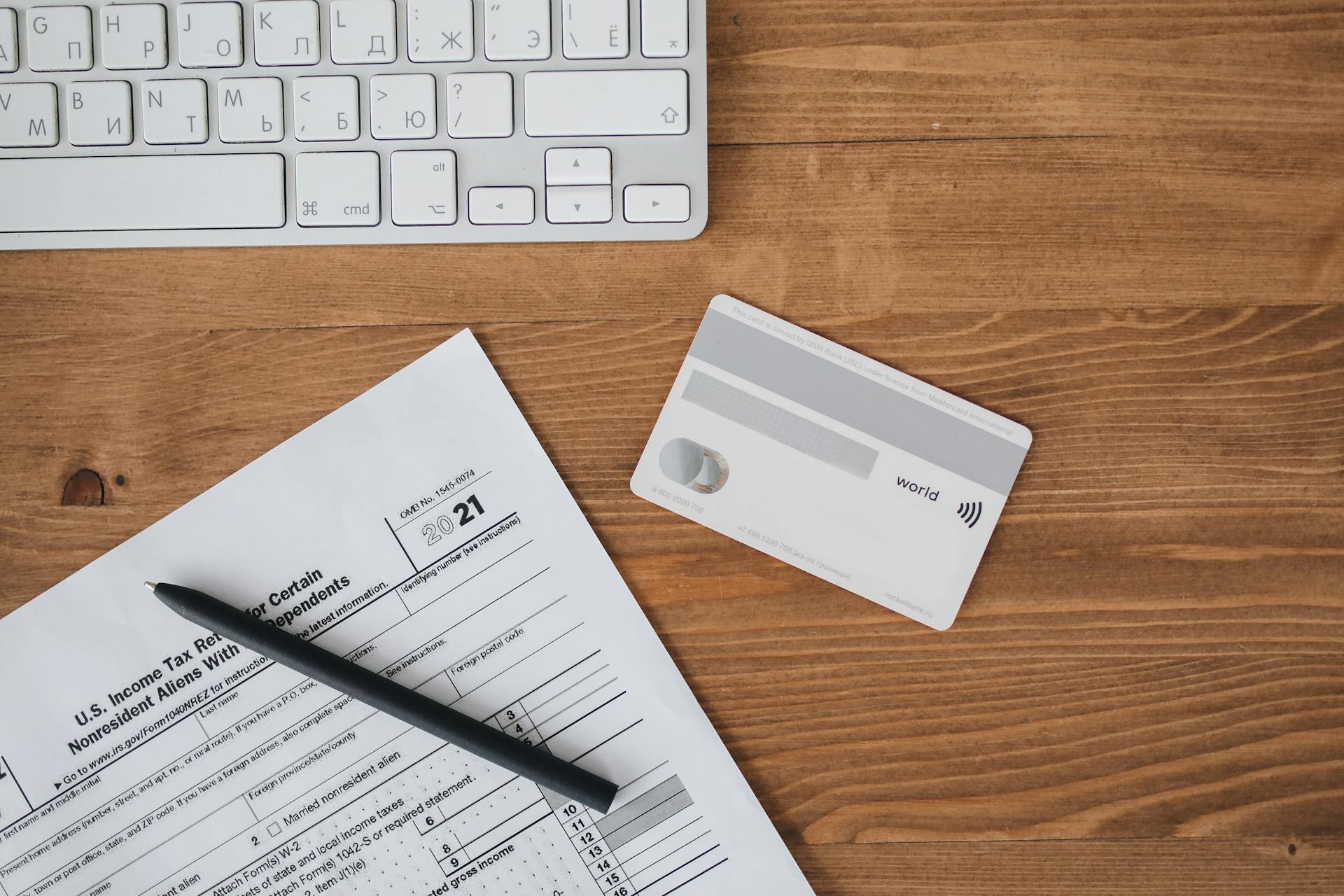 A Debit Card with Paper and Pen on a Wooden Table