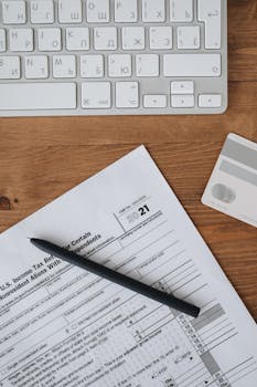 Top view of tax forms, keyboard, and credit card on wooden desk for business preparation.
