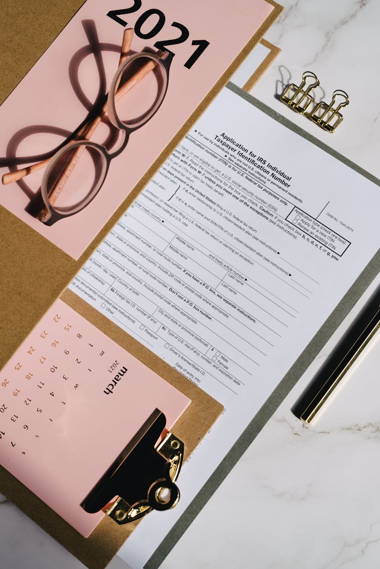 Blank Tax Forms Near A Monthly Calendar On A Clipboard