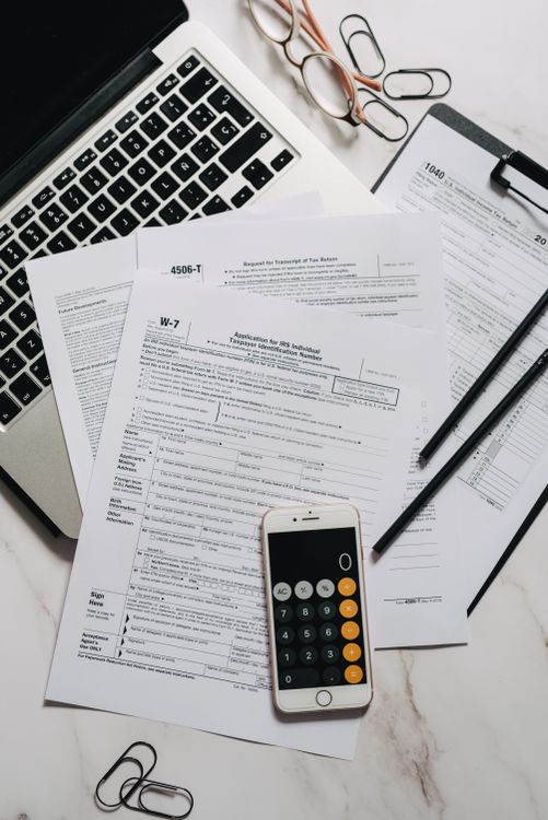 Documentos, calculadora y laptop para organizar información tributaria