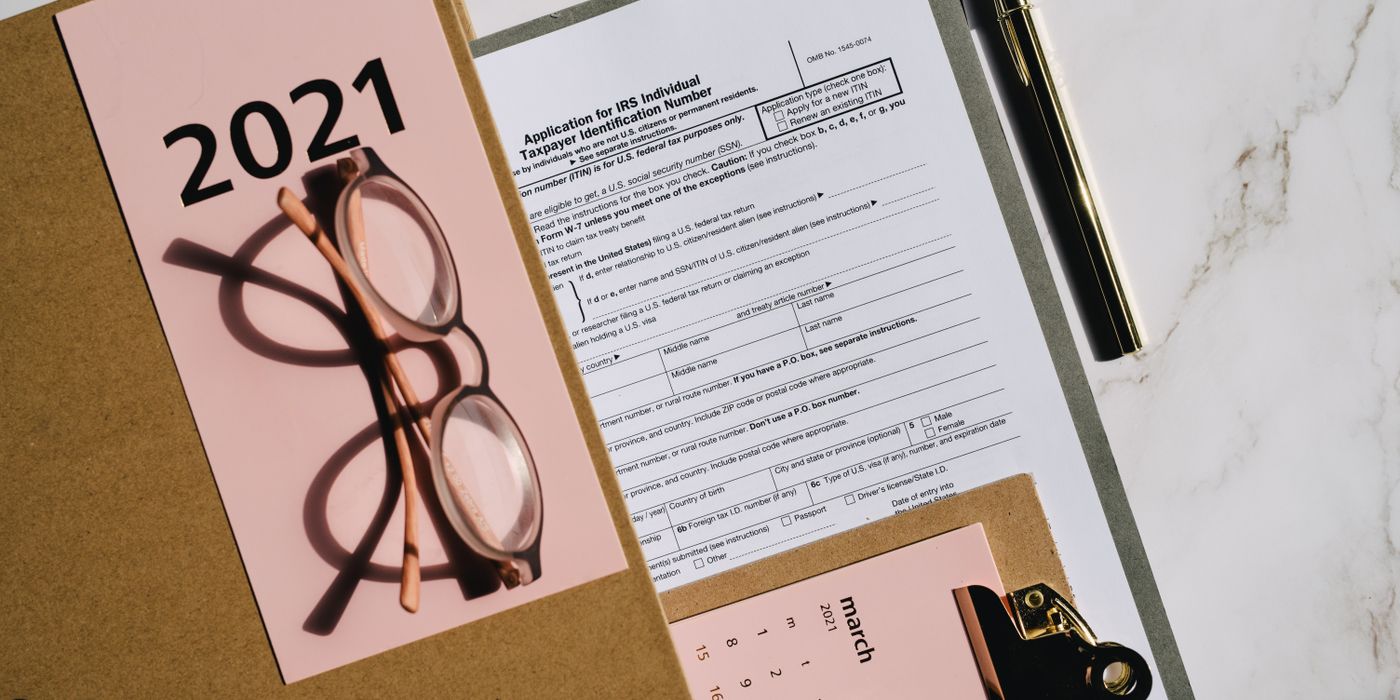 Flat lay of tax forms, calendar, and glasses for 2021 financial planning.