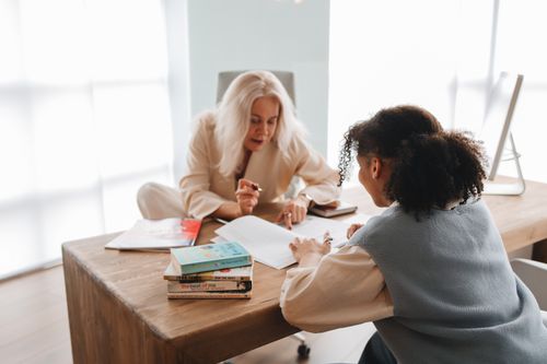 Free A tutor and student engaged in a learning session with books and notes on a table. Stock Photo