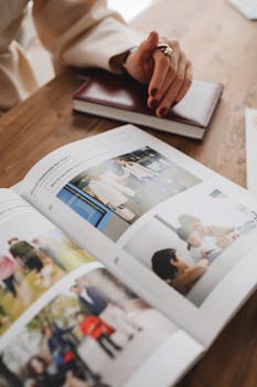 Close-up of an open book on a table with a hand resting nearby, suggesting thoughtful study.