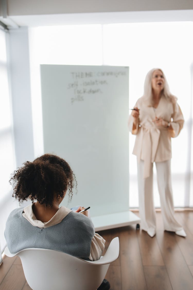 Back View Of A Student Listening To Her Teacher