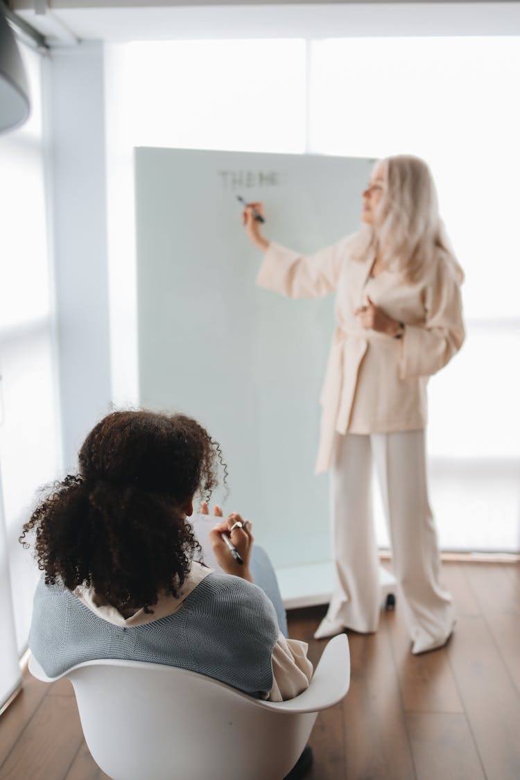 Back View Of A Student Listening To Her Teacher