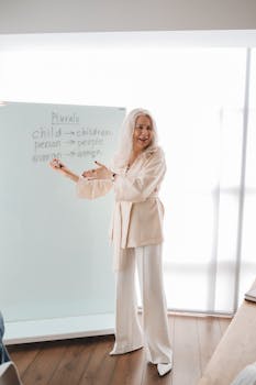 Elderly female instructor teaches English grammar in a bright classroom setting.