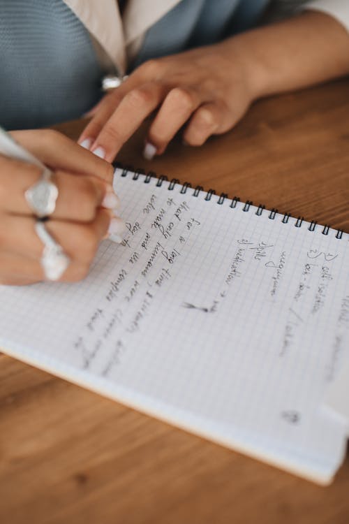 Close-Up View of a Person Writing Notes on a Notebook